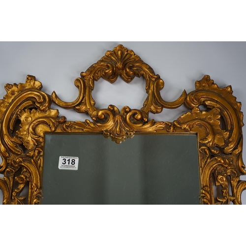 318 - A decorative gilt wall mirror with scroll detail.