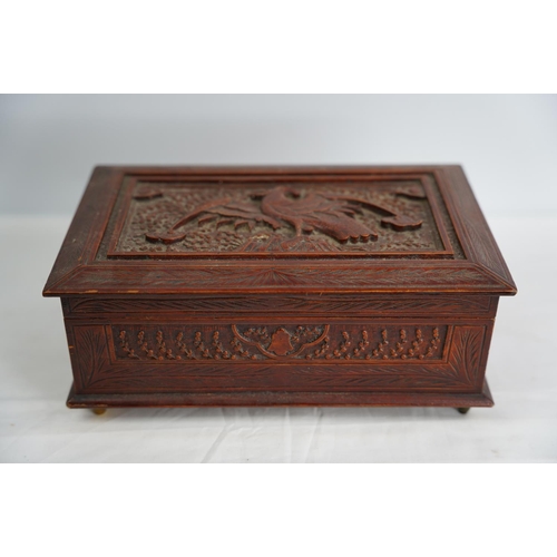 329 - A decorative carved wooden box with eagle design and a collection of sea shells.