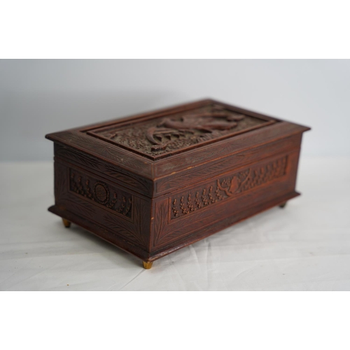 329 - A decorative carved wooden box with eagle design and a collection of sea shells.