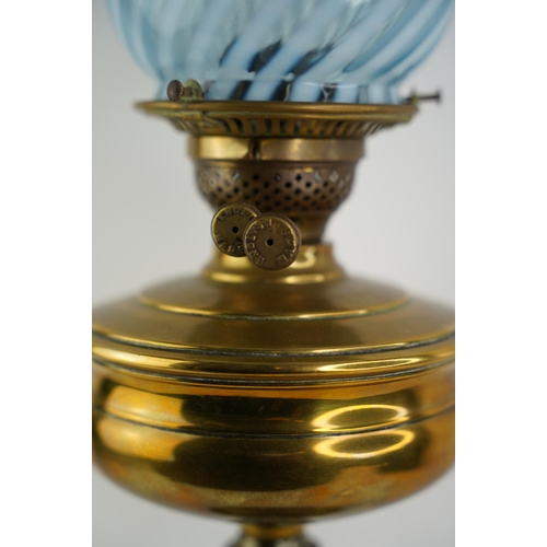 161 - An antique brass font oil lamp with blue striped patterned glass shade.