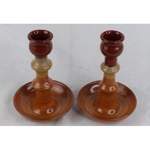 230 - A pair of terracotta glazed candlesticks.