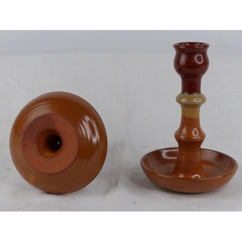 230 - A pair of terracotta glazed candlesticks.