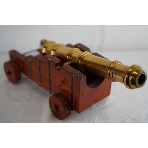 138 - A model brass cannon on wooden stand, measuring 33xm x 14cm.