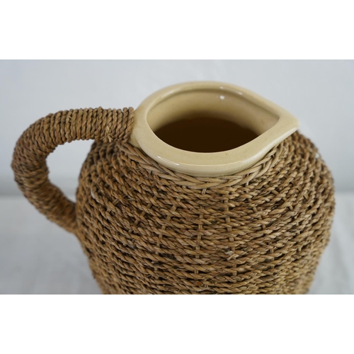 163 - An earthenware water jug with woven basket detail, measuring 21cm.