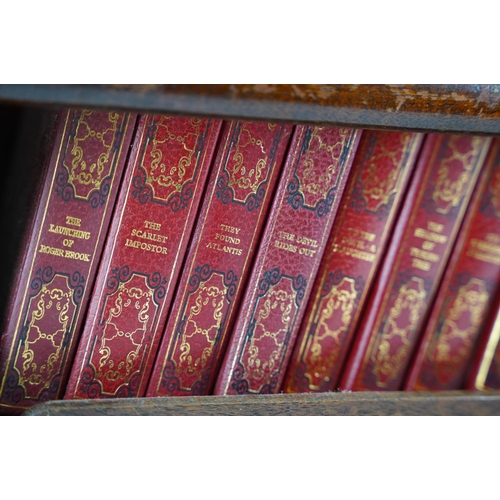 216 - An oak book trough and a set of Dennis Wheatley books.