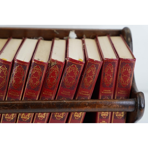 216 - An oak book trough and a set of Dennis Wheatley books.