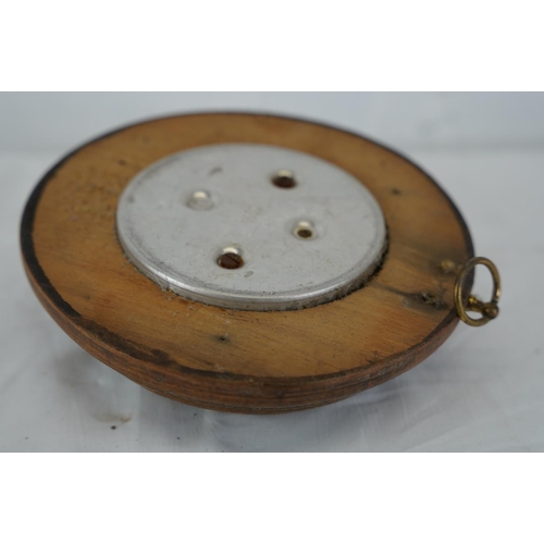 306 - A small circular barometer with ceramic dial and wooden case.