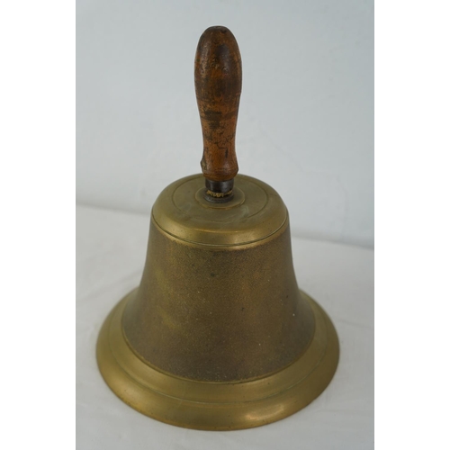 375 - A large heavy brass bell with wooden handle, 26cm.