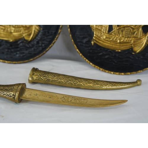 445 - A pair of vintage brass plaques and an ornamental brass dagger.