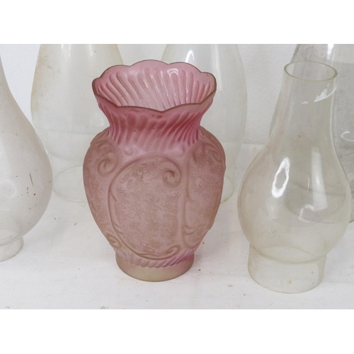 88 - A collection of vintage glass chimneys and a ruby glass shade.