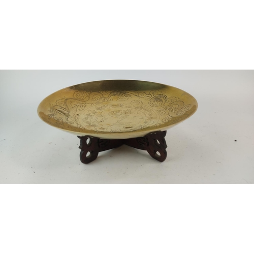 387 - A vintage brass and engraved bowl on a hardwood stand. Diameter measuring 36cm.