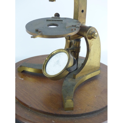 A vintage brass microscope mounted on a wooden base.