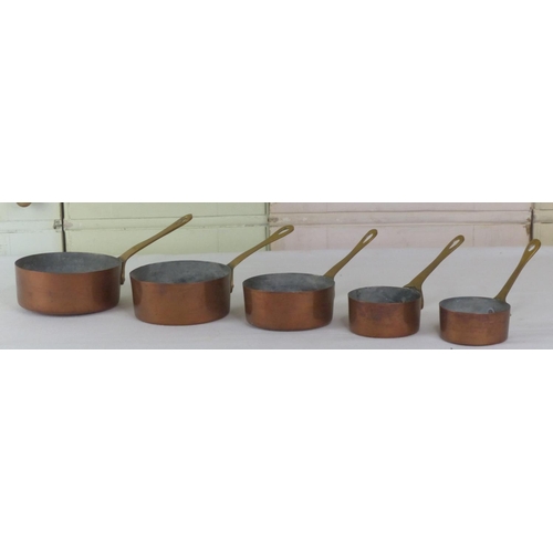 58 - A set of five small graduating copper and brass handled pans.