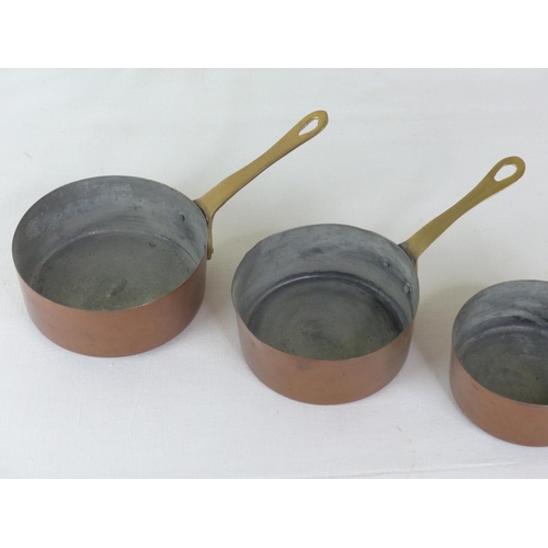 58 - A set of five small graduating copper and brass handled pans.