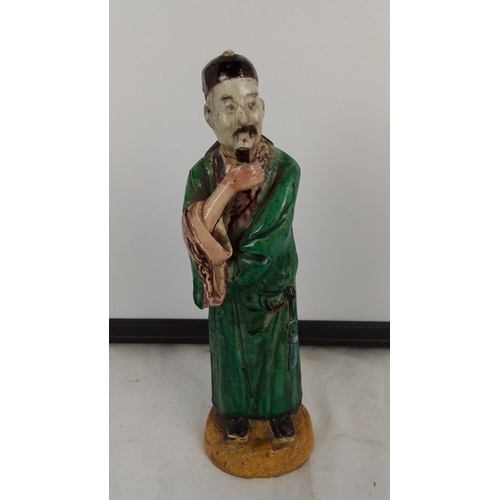 172 - A Chinese salt glazed pottery figure of a scholar in green robes, modelled standing with hand to bea... 