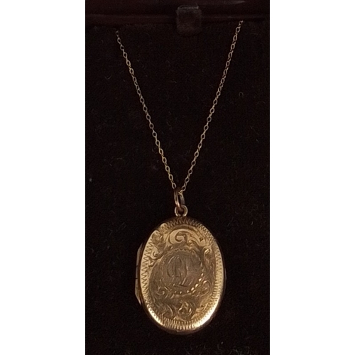 356 - An oval 9ct gold locket pendant, the cover engraved with foliate scrolls and an initialled cartouche... 