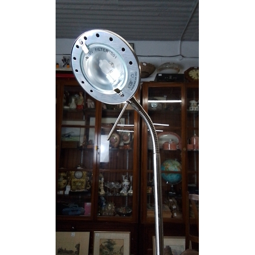 432 - A brushed metal floor lamp with circular perforated shade, adjustable arm and gooseneck stem, on wei... 