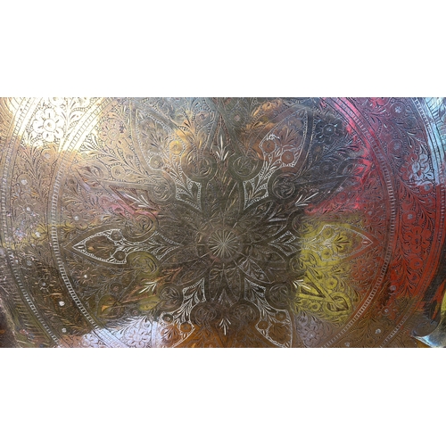 32 - A large circular Middle Eastern style metal tray or charger, with scalloped rim and densely chased f... 