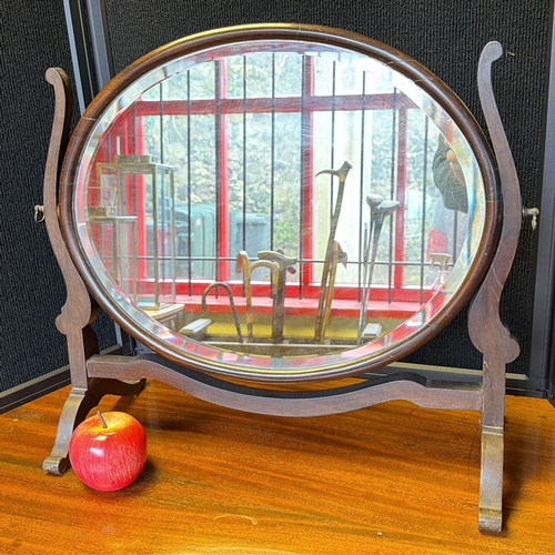 8 - An oval mahogany dressing mirror, the bevelled plate within a swivelling frame, raised on a shaped s... 