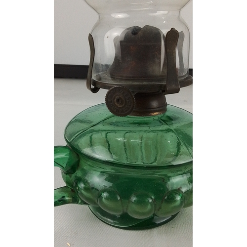 290 - A vintage green glass oil lamp with twin scroll handles, clear glass chimney etched with an eagle mo... 