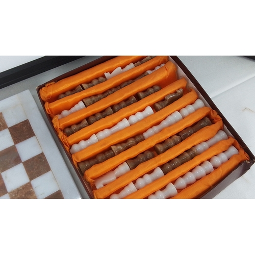 291 - Onyx chess board with alternating white and russet squares, together with a box containing a set of ... 