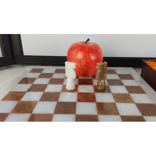 291 - Onyx chess board with alternating white and russet squares, together with a box containing a set of ... 
