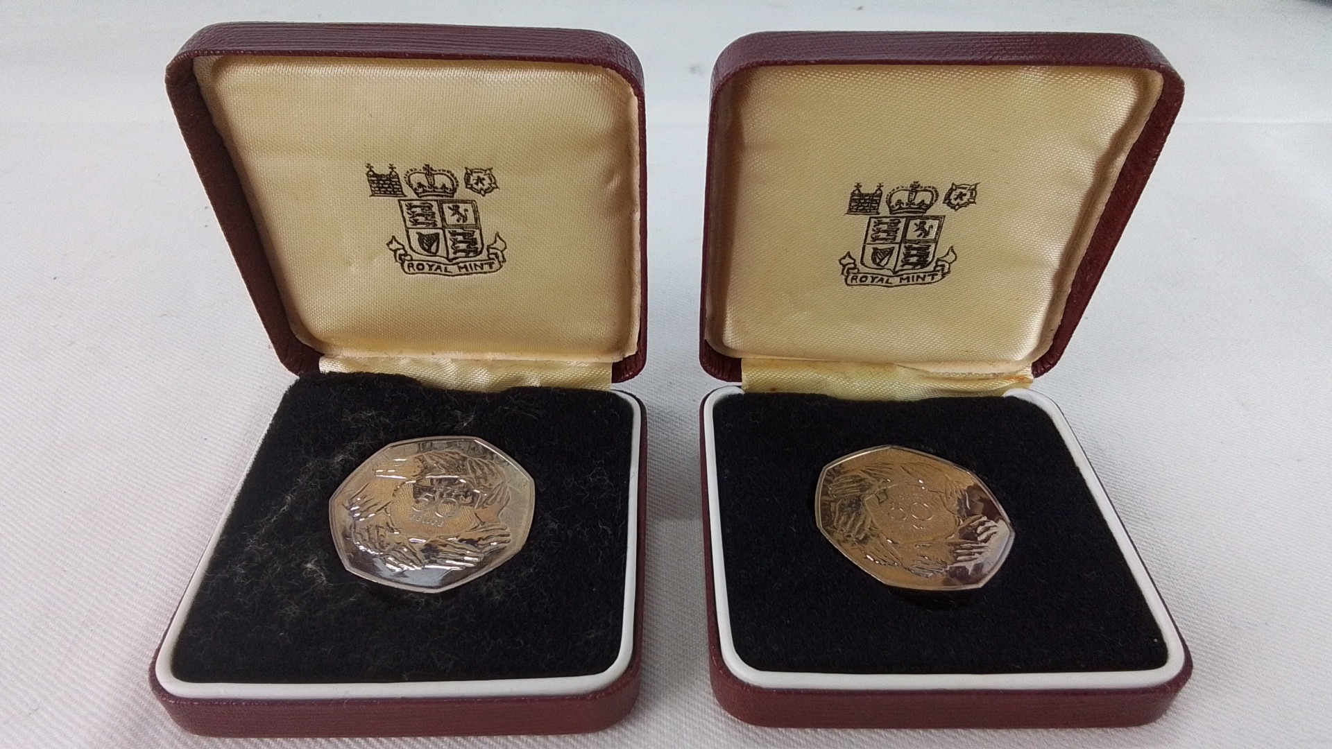 Pair of Royal Mint presentation 50 pence coins, each in original maroon ...