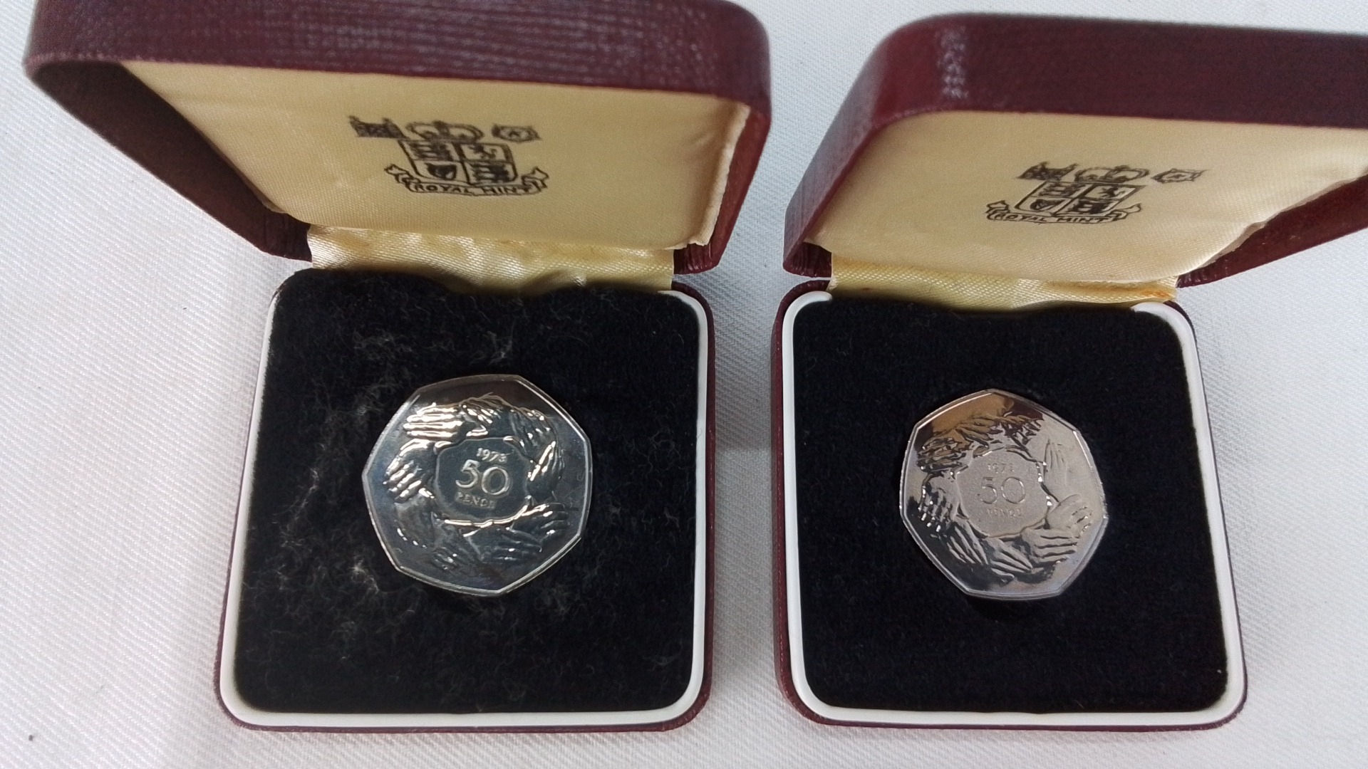 Pair of Royal Mint presentation 50 pence coins, each in original maroon ...