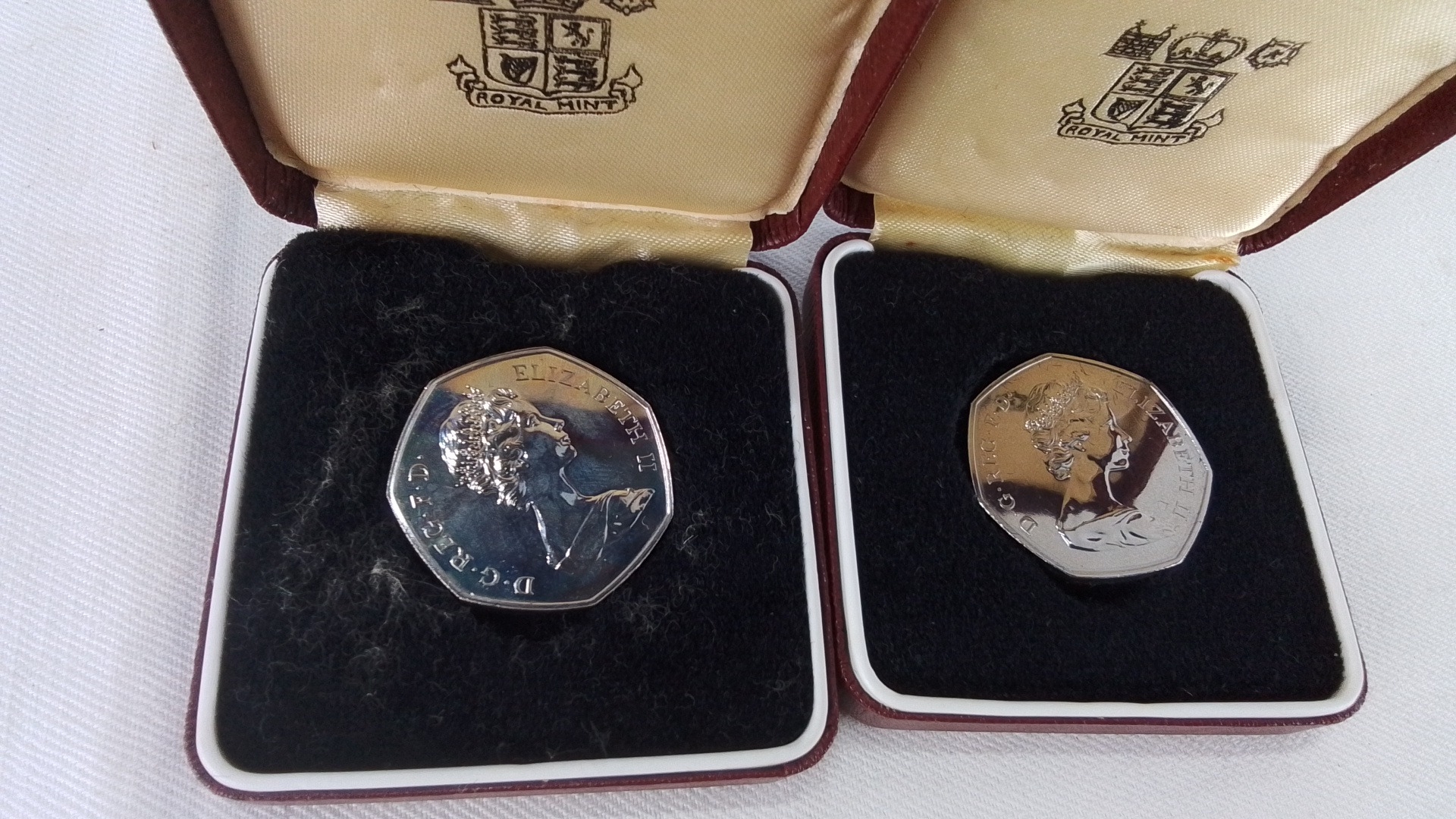 Pair of Royal Mint presentation 50 pence coins, each in original maroon ...