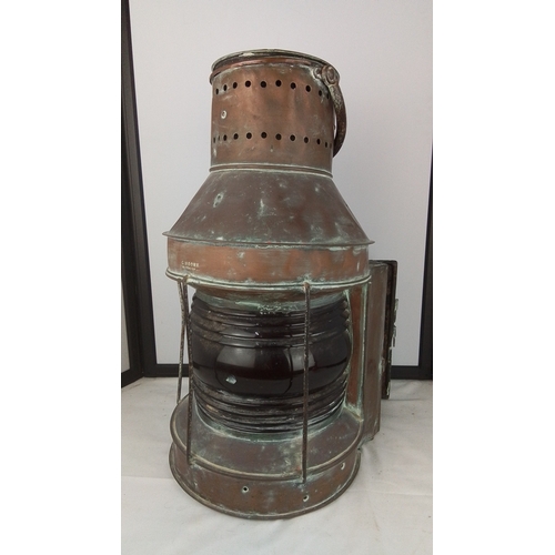 A stunning antique copper-and-brass masthead lantern by G. Moore, Coleraine, with cylindrical pierced chimney, swing handle and riveted construction, the glazed body in deep ruby with protective wire guards and hinged access door, 53cm.