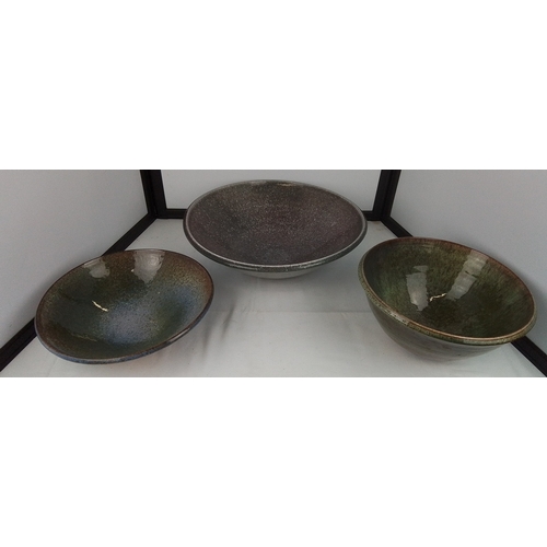 102 - A group of three studio pottery stoneware bowls, one broad shallow dish and two deeper forms, each w... 