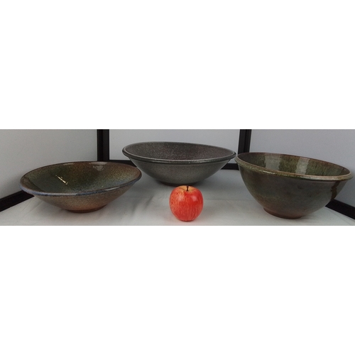 102 - A group of three studio pottery stoneware bowls, one broad shallow dish and two deeper forms, each w... 