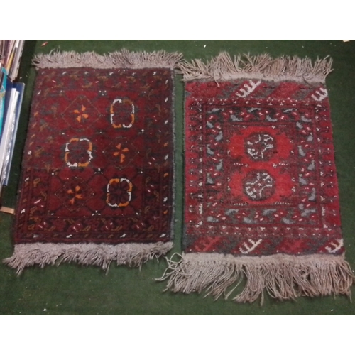 105 - A pair of small wool pile rugs, each with geometric medallion design in red and indigo tones, within... 