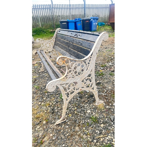 134 - Cast-iron garden bench with pierced scrolling end supports and rosette roundels, fitted with black-p... 