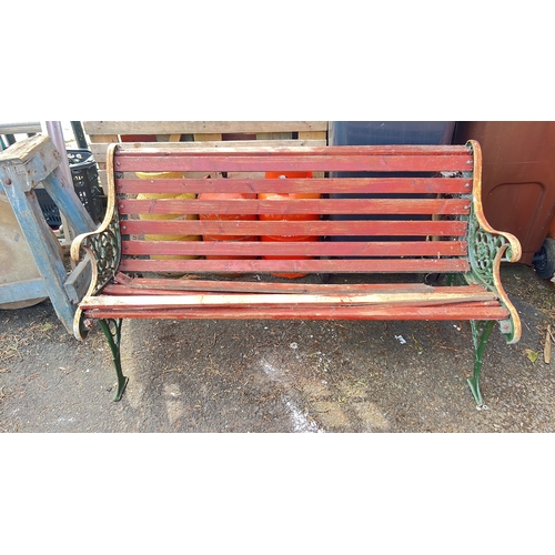 54 - Garden bench with red-painted slatted timber seat and back, on green cast-iron ends with pierced flo... 