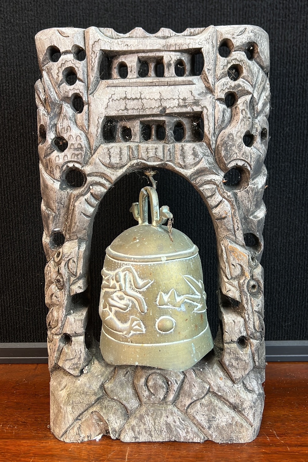 Cast-metal bell suspended within a carved wooden stand with pierced ...