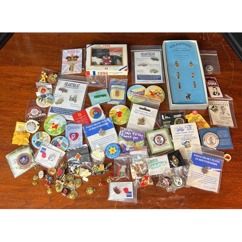 A collection of enamel lapel badges and pictorial pin-back buttons ...