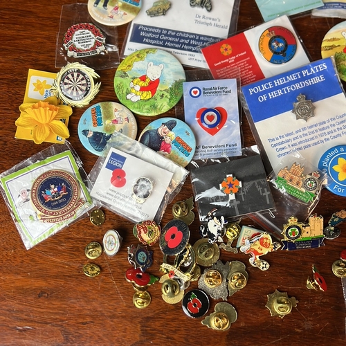 A collection of enamel lapel badges and pictorial pin-back buttons ...