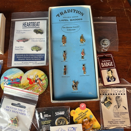 A collection of enamel lapel badges and pictorial pin-back buttons ...