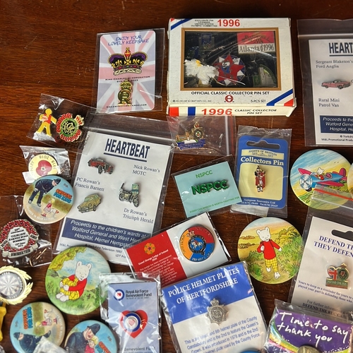 A collection of enamel lapel badges and pictorial pin-back buttons ...