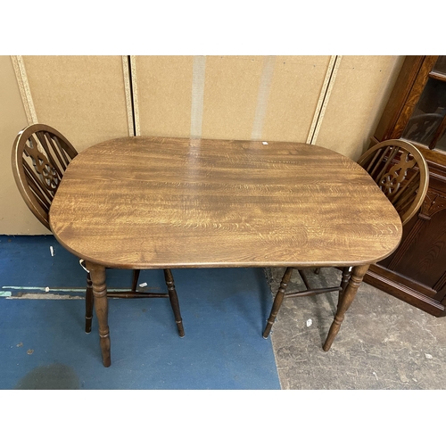 194 - OAK EFFECT OVAL DINING TABLE AND PAIR OF WHEELBACK CHAIRS