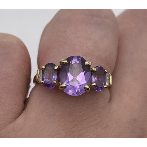 553 - 9CT GOLD STEPPED THREE STONE AMETHYST RING WITH TWIN DIAMOND CHIP SHOULDERS SIZE N 2.6G APPROX