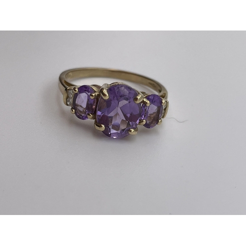 553 - 9CT GOLD STEPPED THREE STONE AMETHYST RING WITH TWIN DIAMOND CHIP SHOULDERS SIZE N 2.6G APPROX