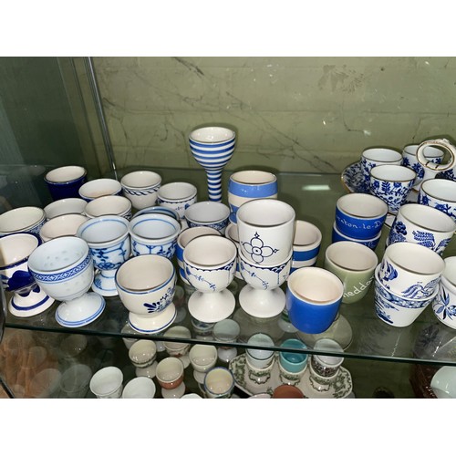 203 - SHELF OF BLUE AND WHITE CORNISH AND WILLOW PATTERN EGG CUPS AND CRUET, MASONS SPODE, POOLE, AND WEDG... 