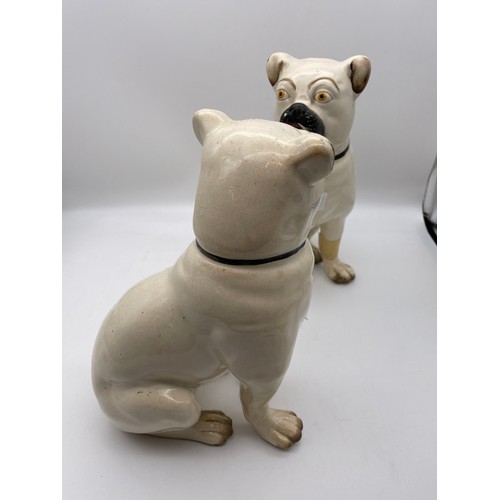 431 - PAIR OF STAFFORDSHIRE POTTERY SEATED PUG DOGS ONE WITH FOOT A/F 27cm