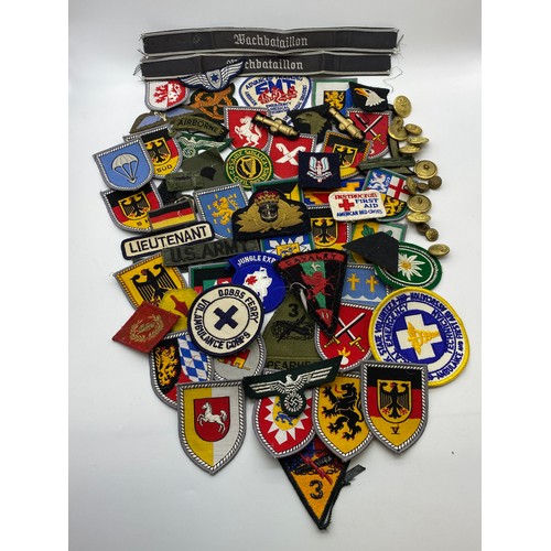 437 - BOX OF BRASS TUNIC BADGES, GERMAN AND OTHER SEW ON PATCHES, AND A TEATOWEL OF REGIMENTAL BADGES OF T... 