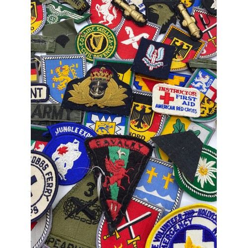 437 - BOX OF BRASS TUNIC BADGES, GERMAN AND OTHER SEW ON PATCHES, AND A TEATOWEL OF REGIMENTAL BADGES OF T... 