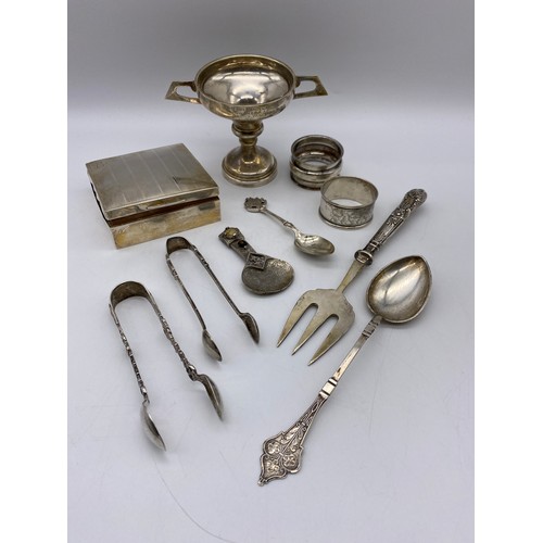 649 - SILVER CIGARETTE BOX, SILVER PRESENTATION TROPHY, NAPKIN RINGS, SILVER SUGAR NIPS AND WHITE METAL SP... 