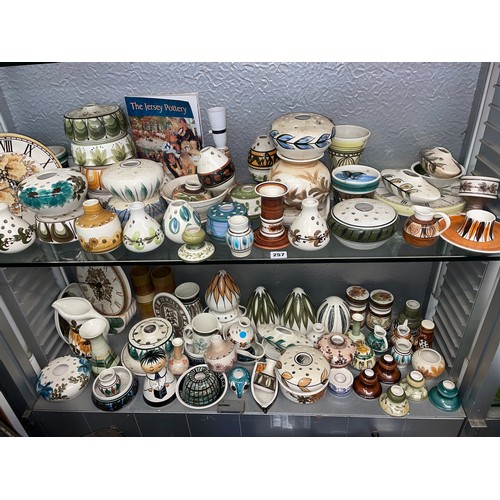 257 - TWO SHELVES OF JERSEY POTTERY INCLUDING QUARTZ WALL CLOCKS, VASES, ROSE BOWLS, ETC