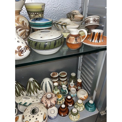 257 - TWO SHELVES OF JERSEY POTTERY INCLUDING QUARTZ WALL CLOCKS, VASES, ROSE BOWLS, ETC